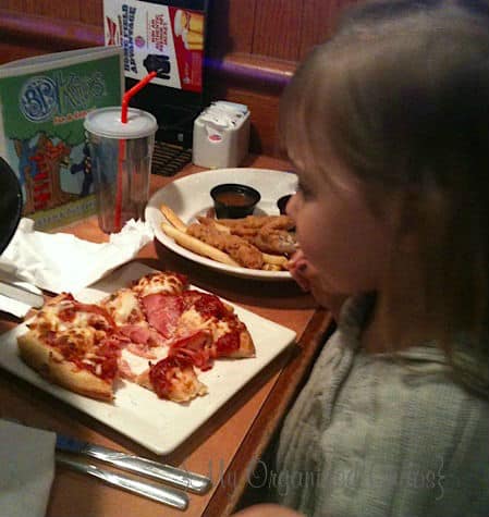A person sitting at a table with a plate of food, with Pizza
