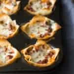 A close up of a slice of cooked lasagna cups in a baking pan