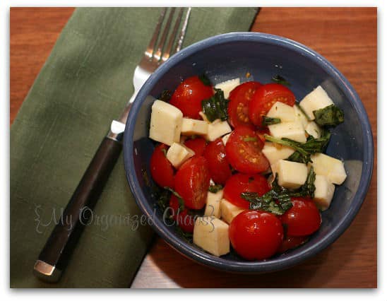 A bowl of food on a table, with Salad and Tomato