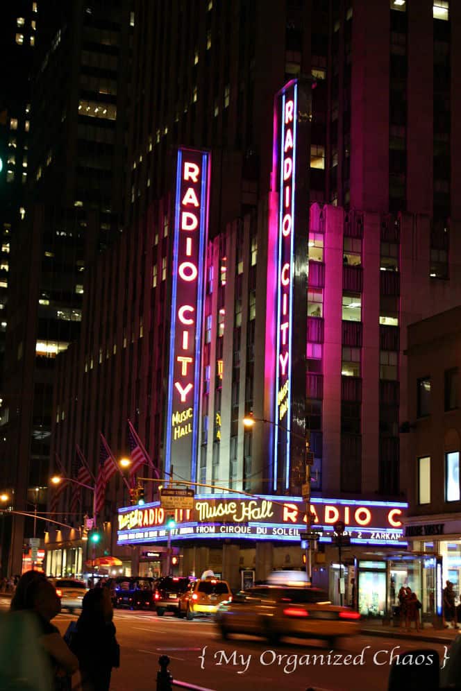 A lit up city at night with Radio City Music Hall in the background, new york