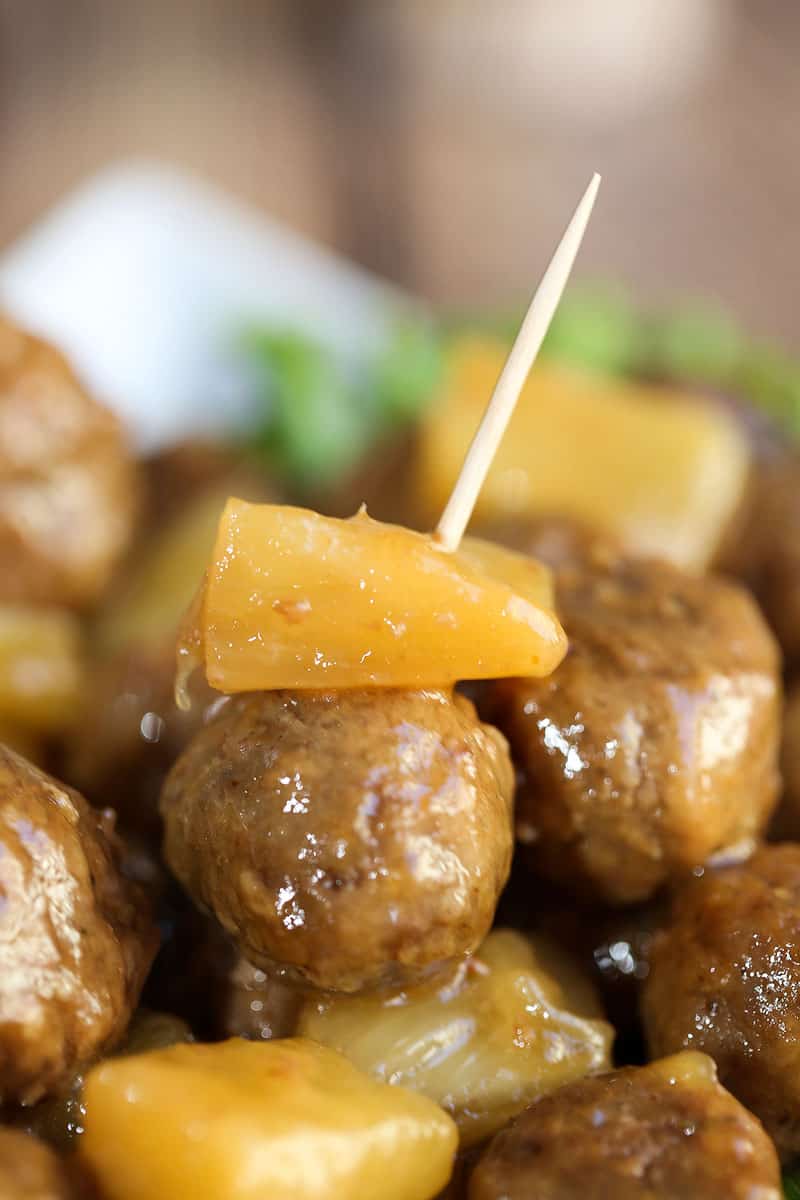 A close up of a plate of food, with Meatball and pineapple