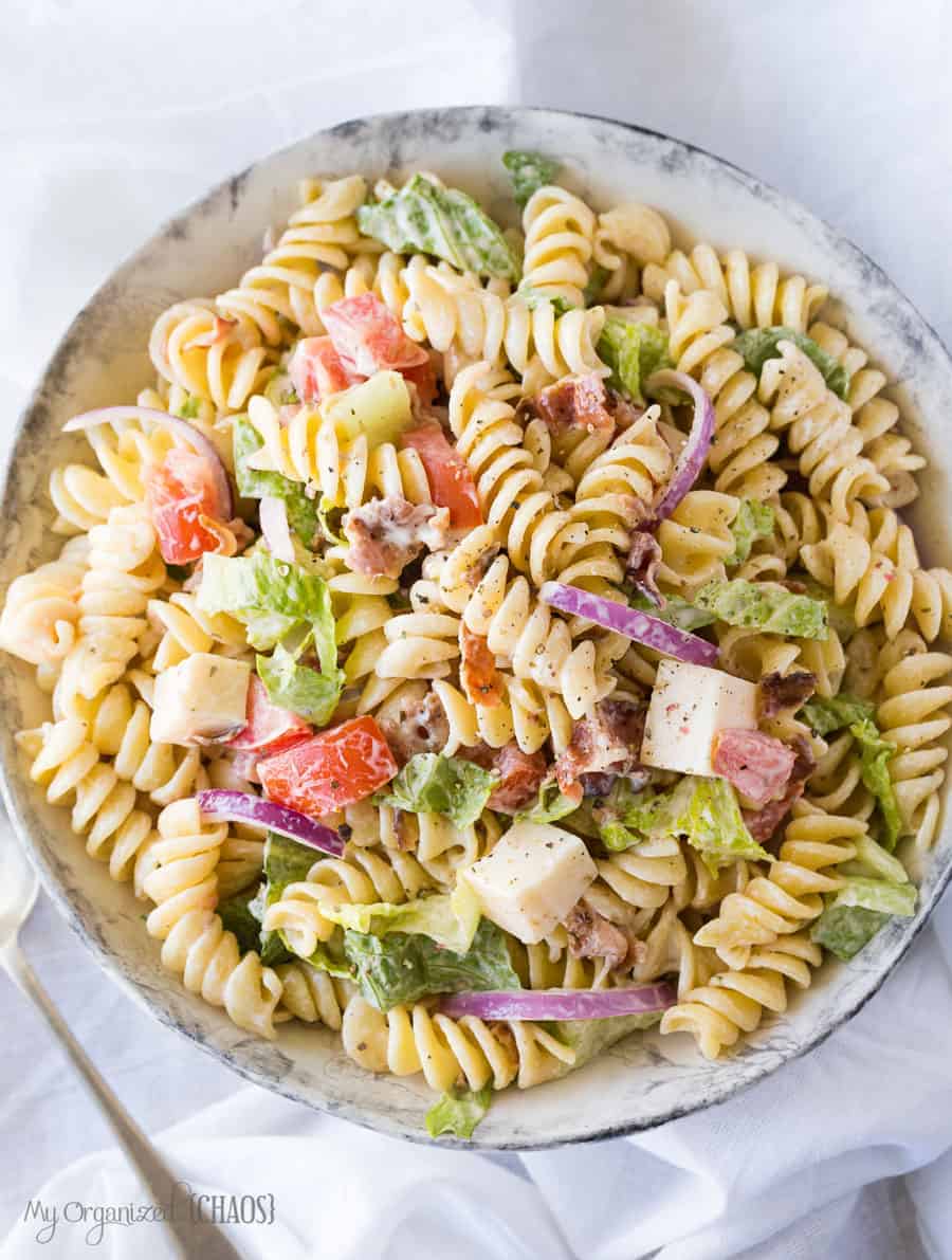 A bowl filled with pasta and salad on a plate, with BLT Pasta Salad