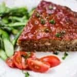 meatloaf made with stove top stuffing on a white plate with a side of fresh vegetables.