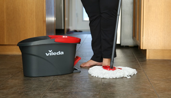 A person standing on the floor with spin mop