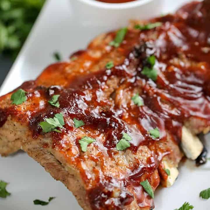 A close up of a plate of food with a slice of pizza, with Ribs and Sauce