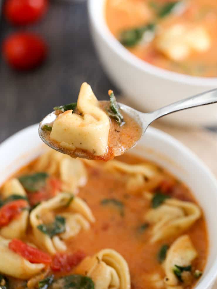 A bowl of food on a plate, with Soup and Tortellini