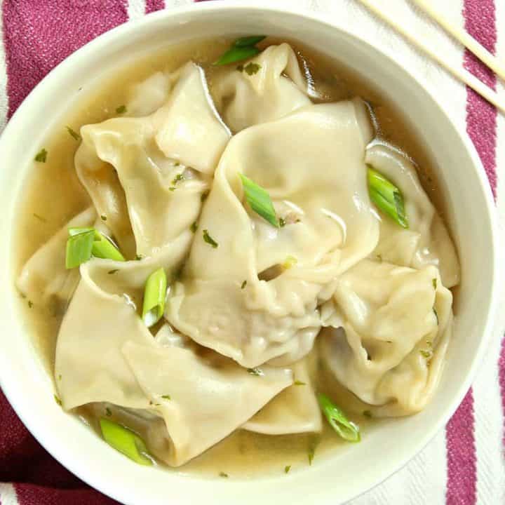 A bowl of food on a plate, with Wonton Soup 