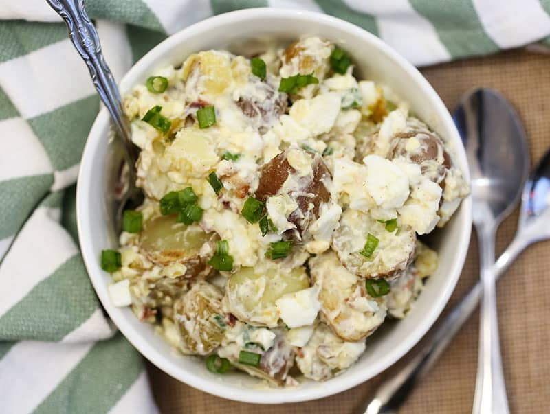 A bowl of food on a plate, with Potato salad