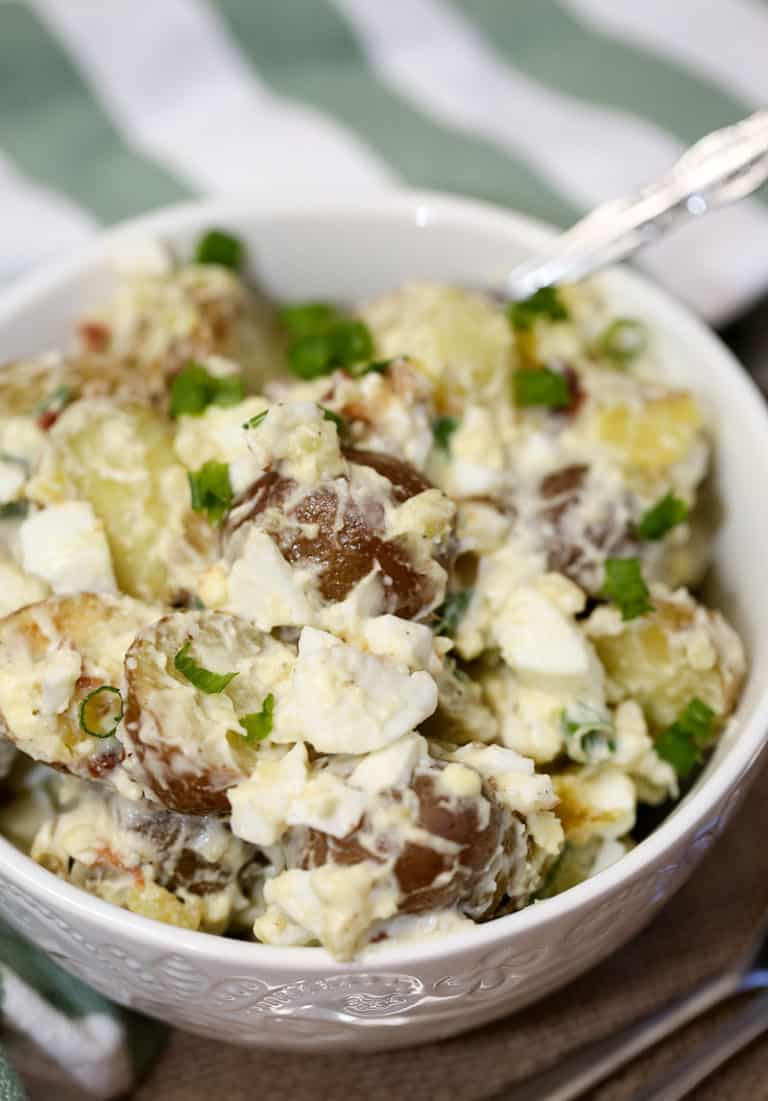 A bowl of food on a plate, with Potato and Salad