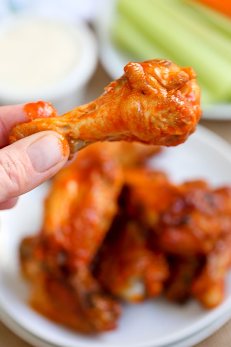 A close up of a person holding a Buffalo chicken wing