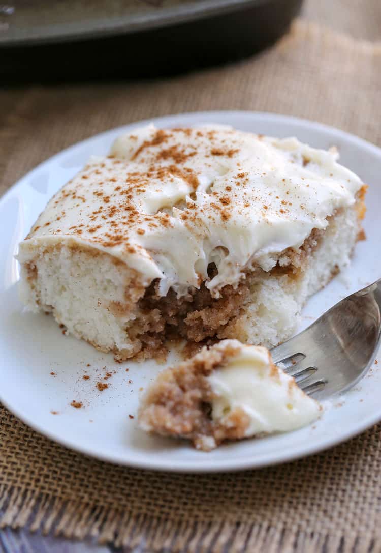 A piece of cake on a plate, with Cinnamon Roll Poke Cake