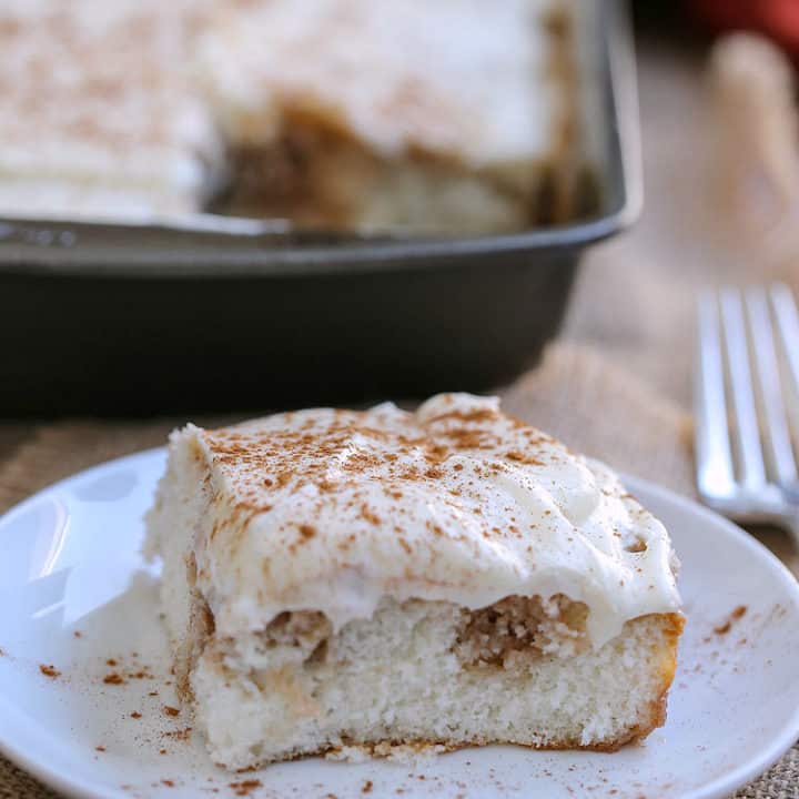 A piece of cake on a plate, with Cinnamon Roll Poke Cake 