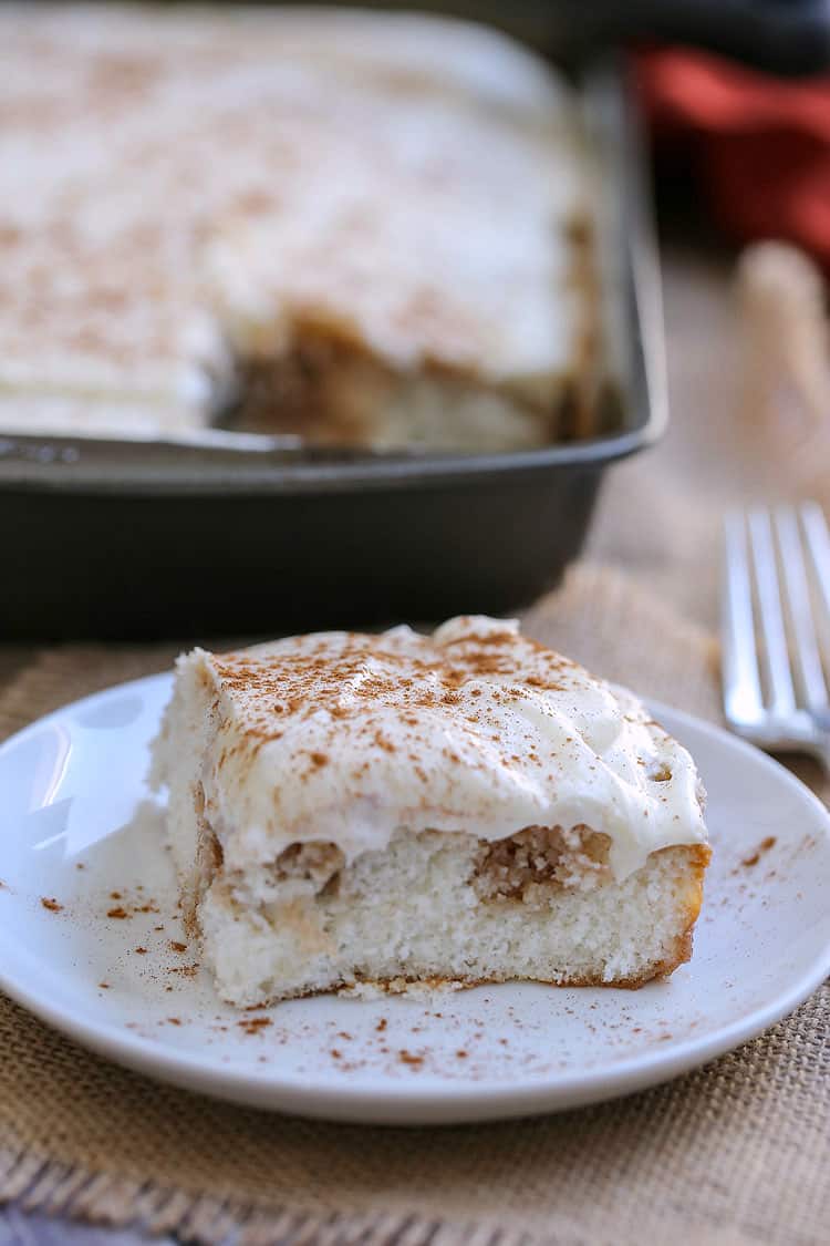 A piece of cake on a plate, with Cinnamon Roll Poke Cake 