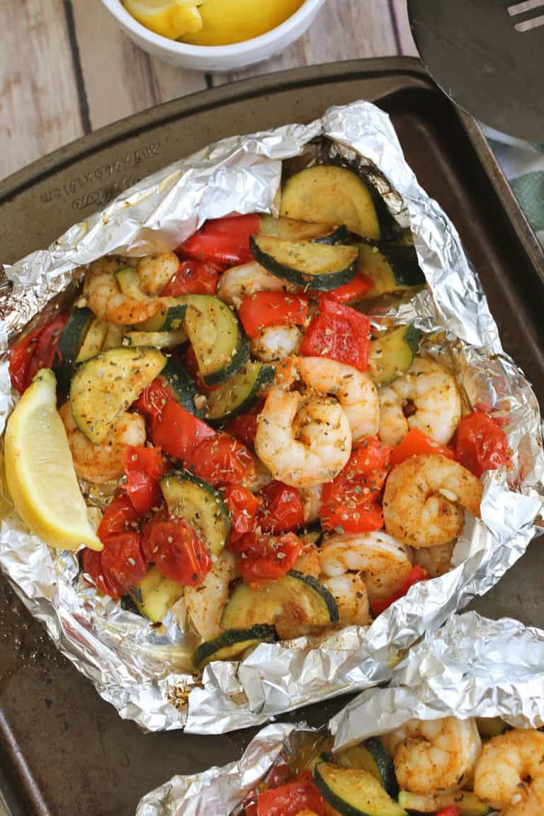 shrimp and fresh vegetables in foil packs with spices and fresh lemon wedge.