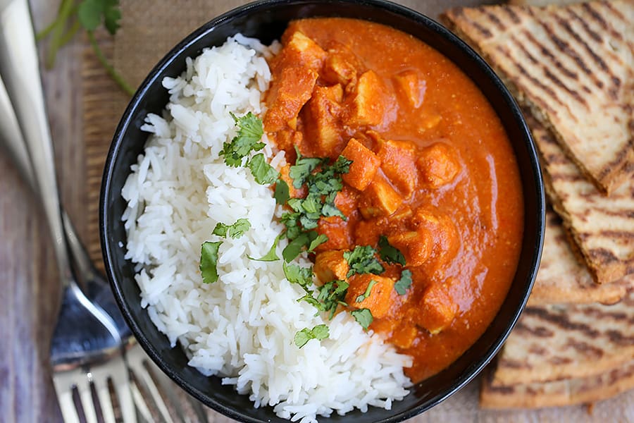 A bowl of rice on a plate, with Slow cooker butter chicken 