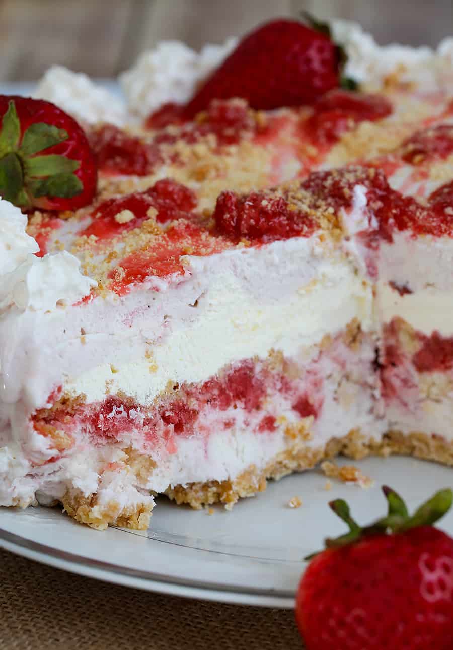 a whole strawberry ice cream cake with a slice taken out