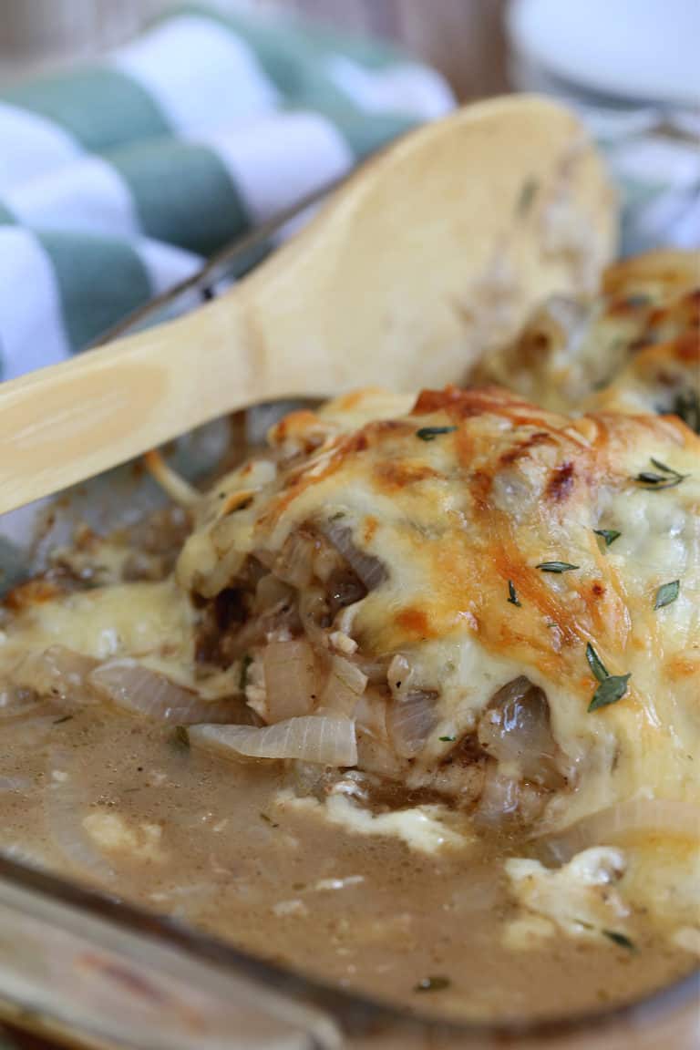 chicken with cheese and onion in a dish with a wooden spoon