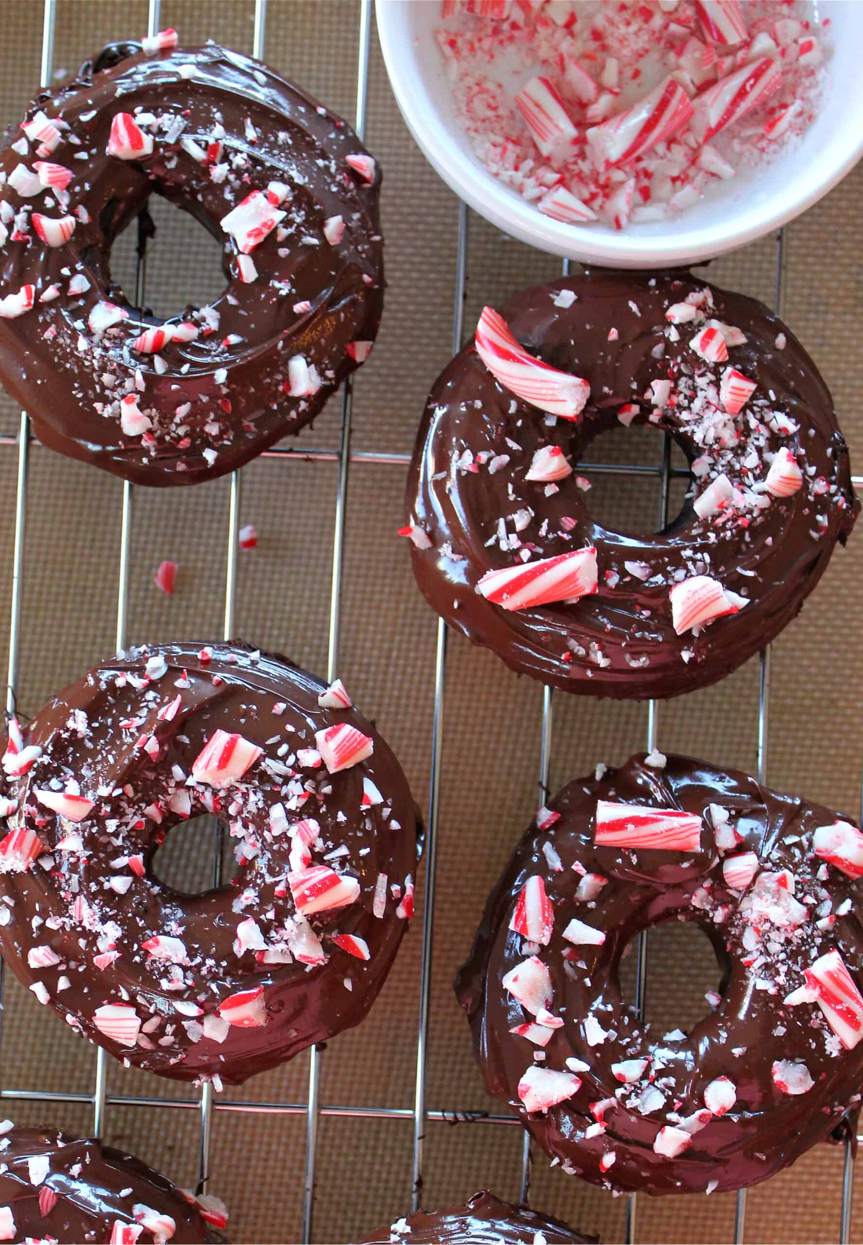 peppermint mocha baked donuts on a cooling rack with bowl of crushed peppermint