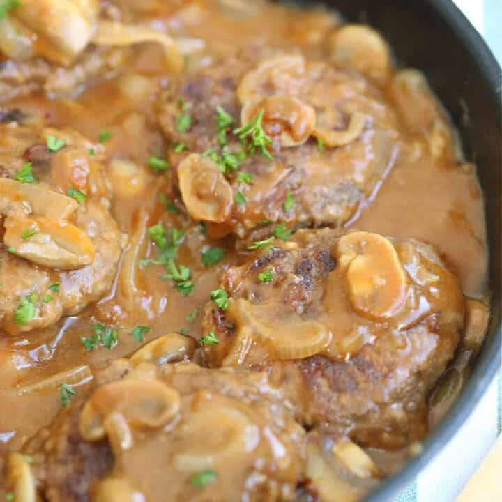 salisbury steak in a frying pan with mushrooms and onions
