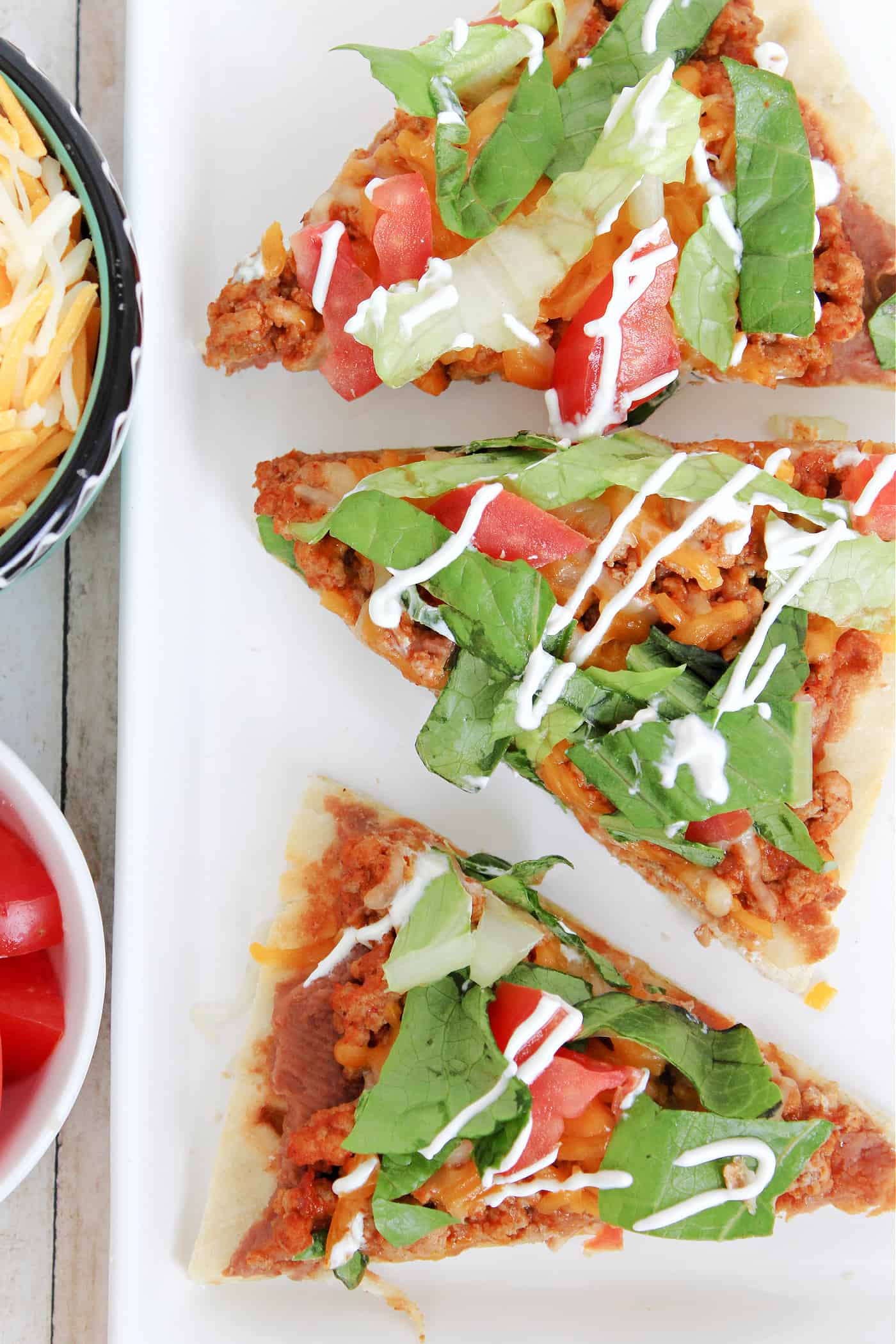 flatbread pizza slices on a plate with a bowl of cheese and tomatoes