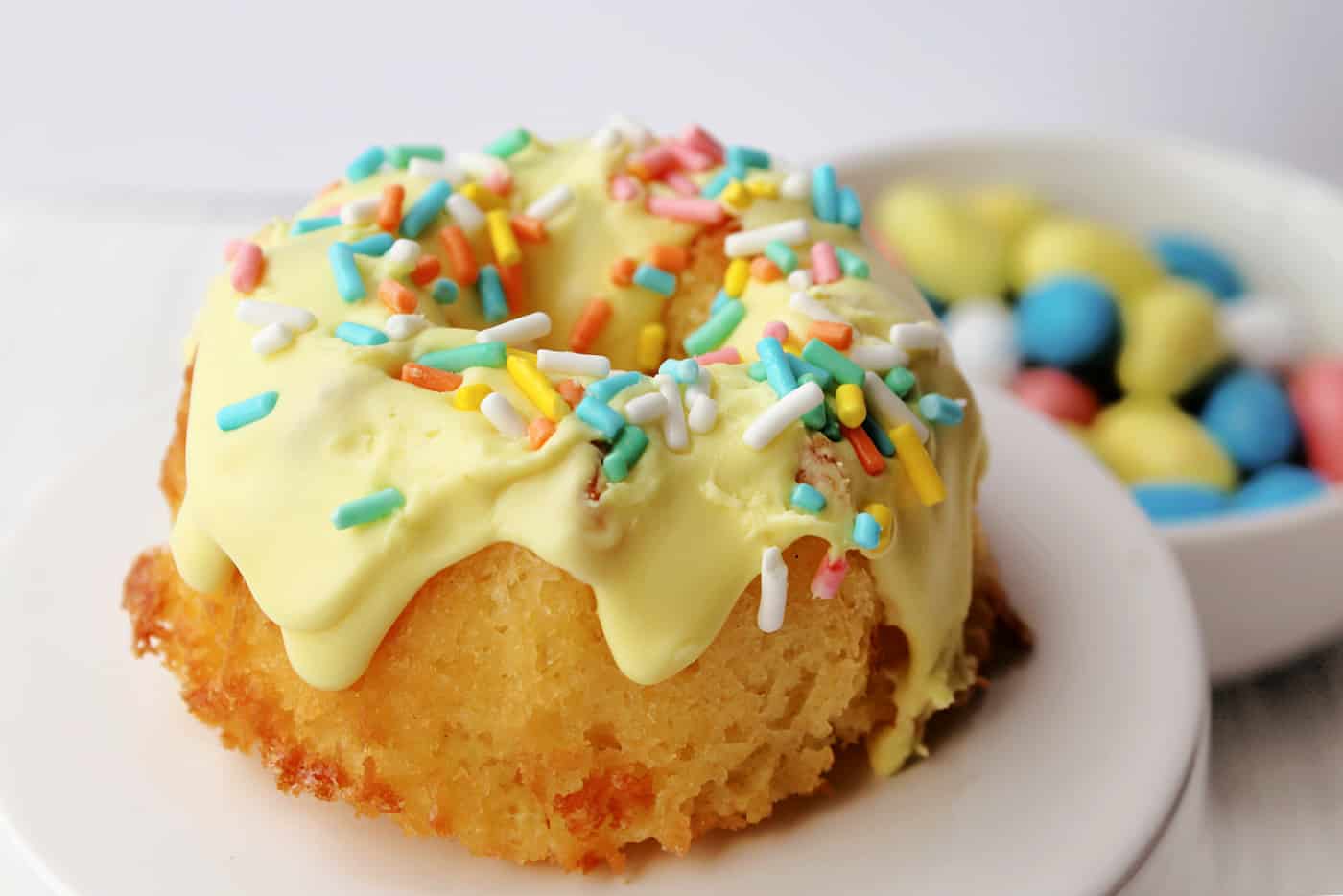 mini decorated bundt cake with yellow frosting on a cake stand