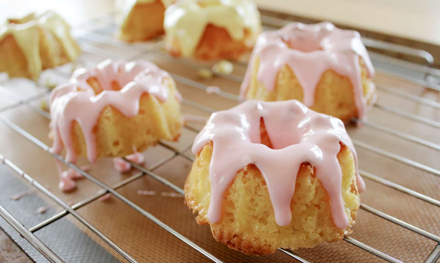 mini bundt cakes with icing on top cooling on a rack