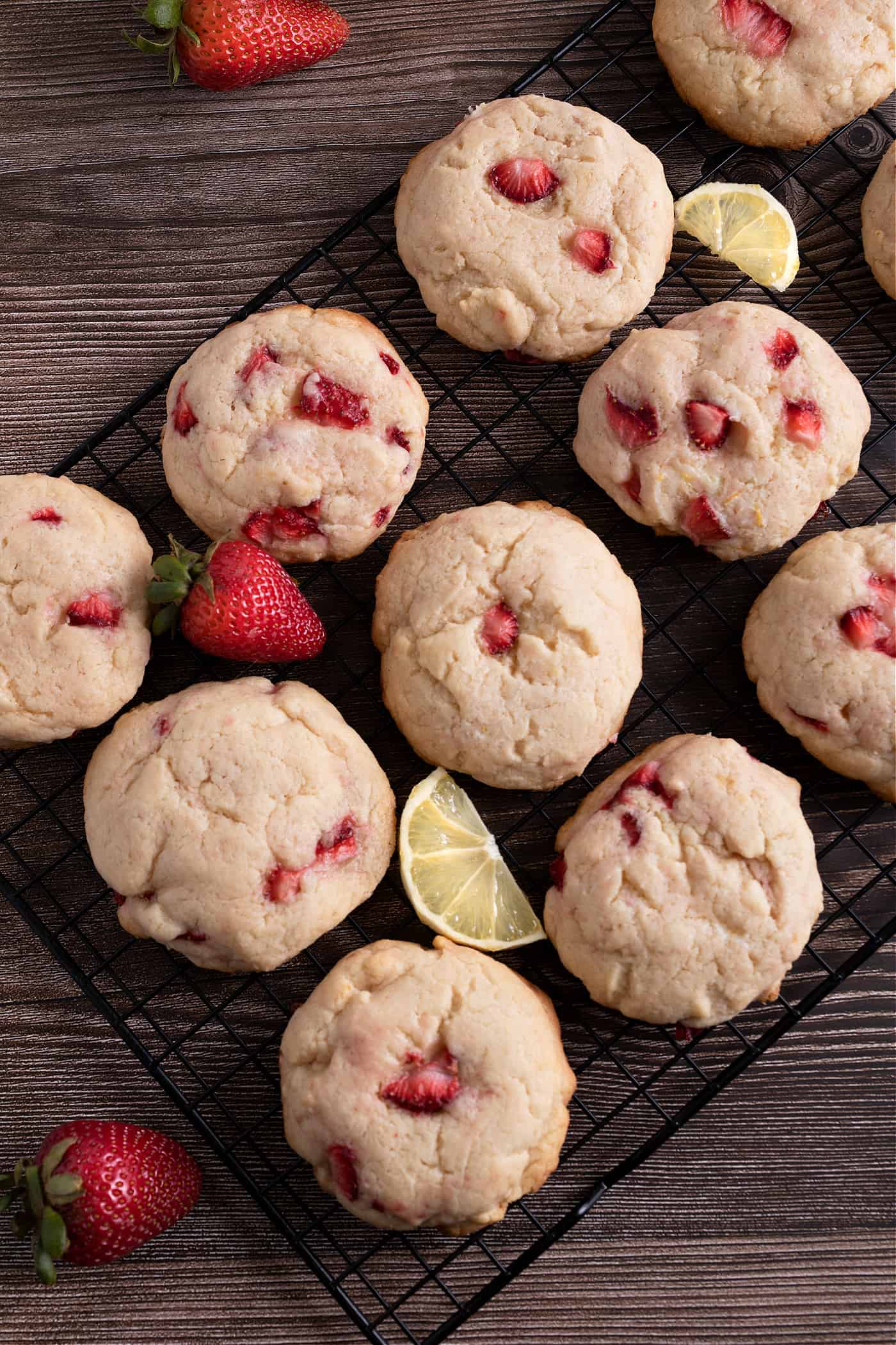 strawberry lemonade cream cheese cookies on a cooling rack with fresh berries and lemon