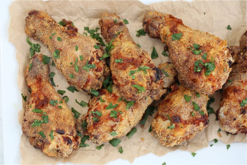 fried chicken drumsticks on brown paper with parsley