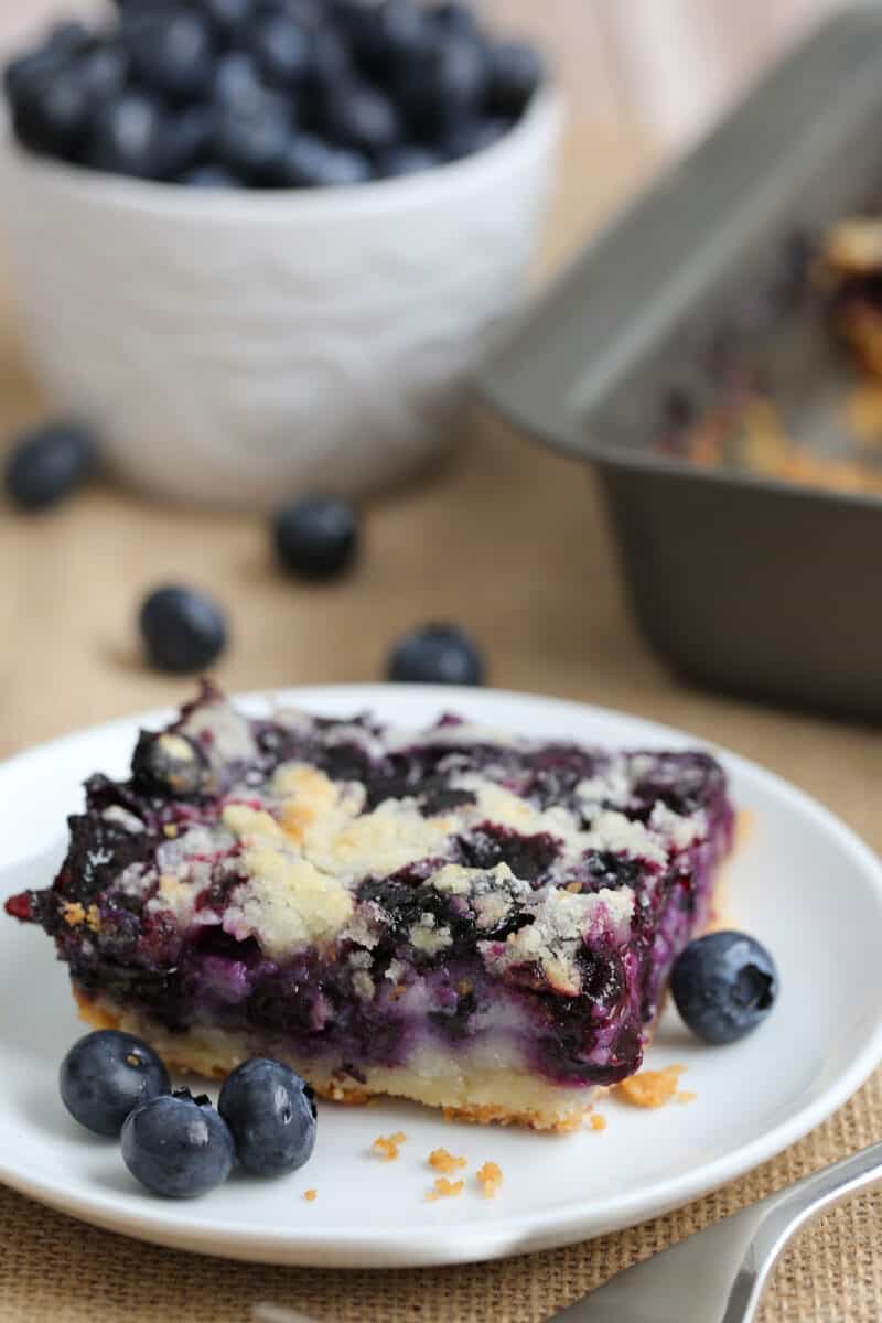 a slice of blueberry bar dessert on a plate with fresh blueberries