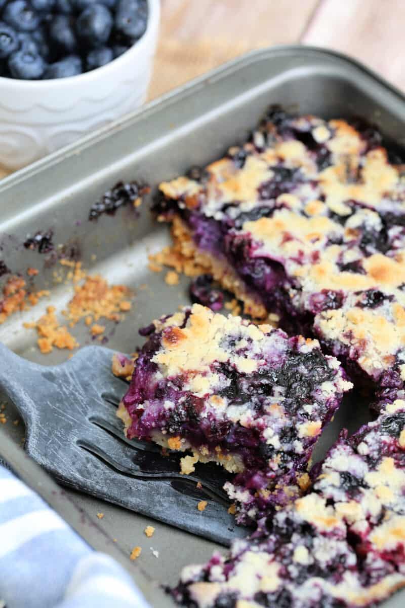 a cut piece of blueberry bar being lifted form a pan with a spatula