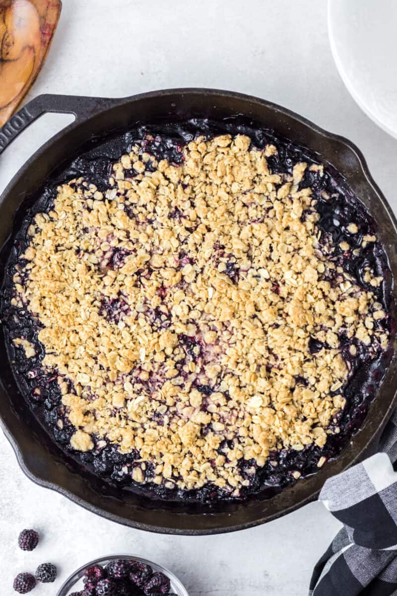 crisp in a cast iron pan on a table with a crunchy oat topping