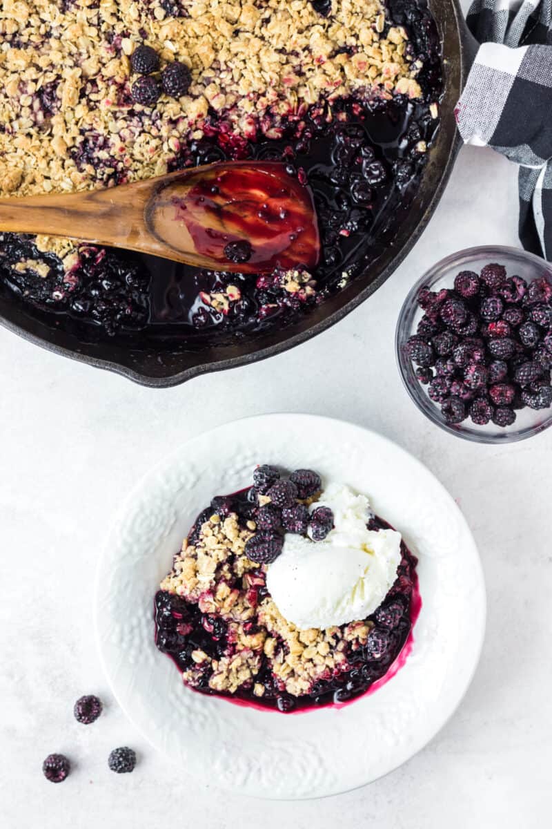 raspberry crumble in a cast iron pan and white bowl on a table