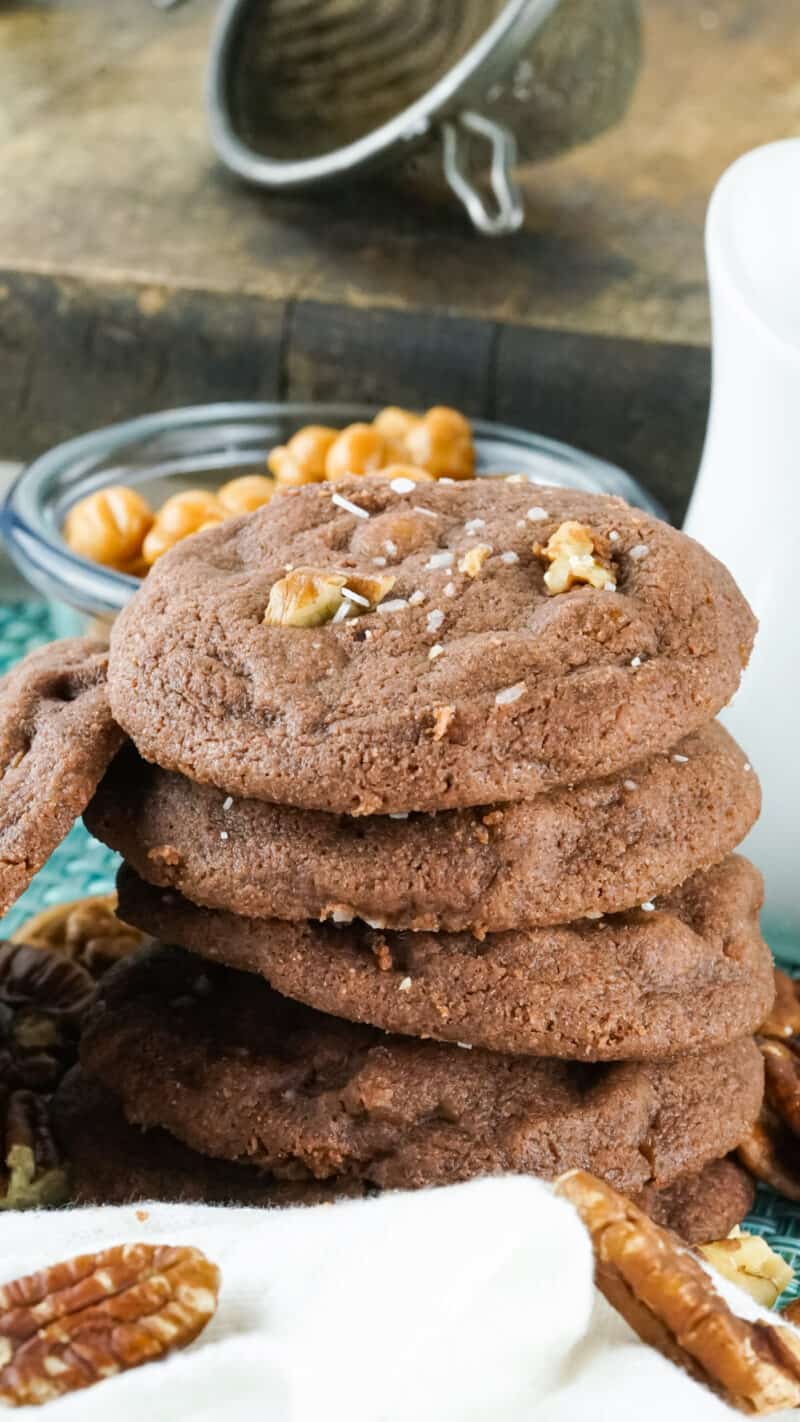 a stack of salted caramel chocolate chip cookies beside a bowl of caramels