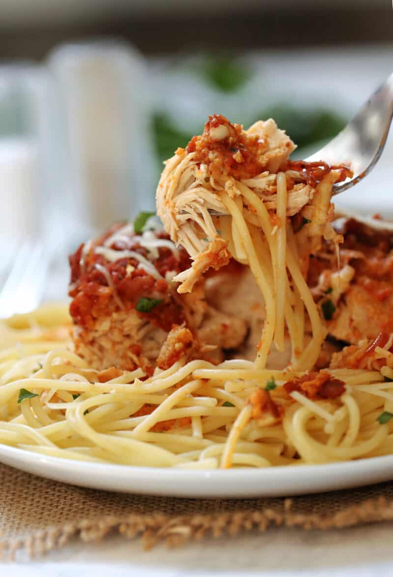 chicken parmesan and spaghetti being lifted by a fork on a plate