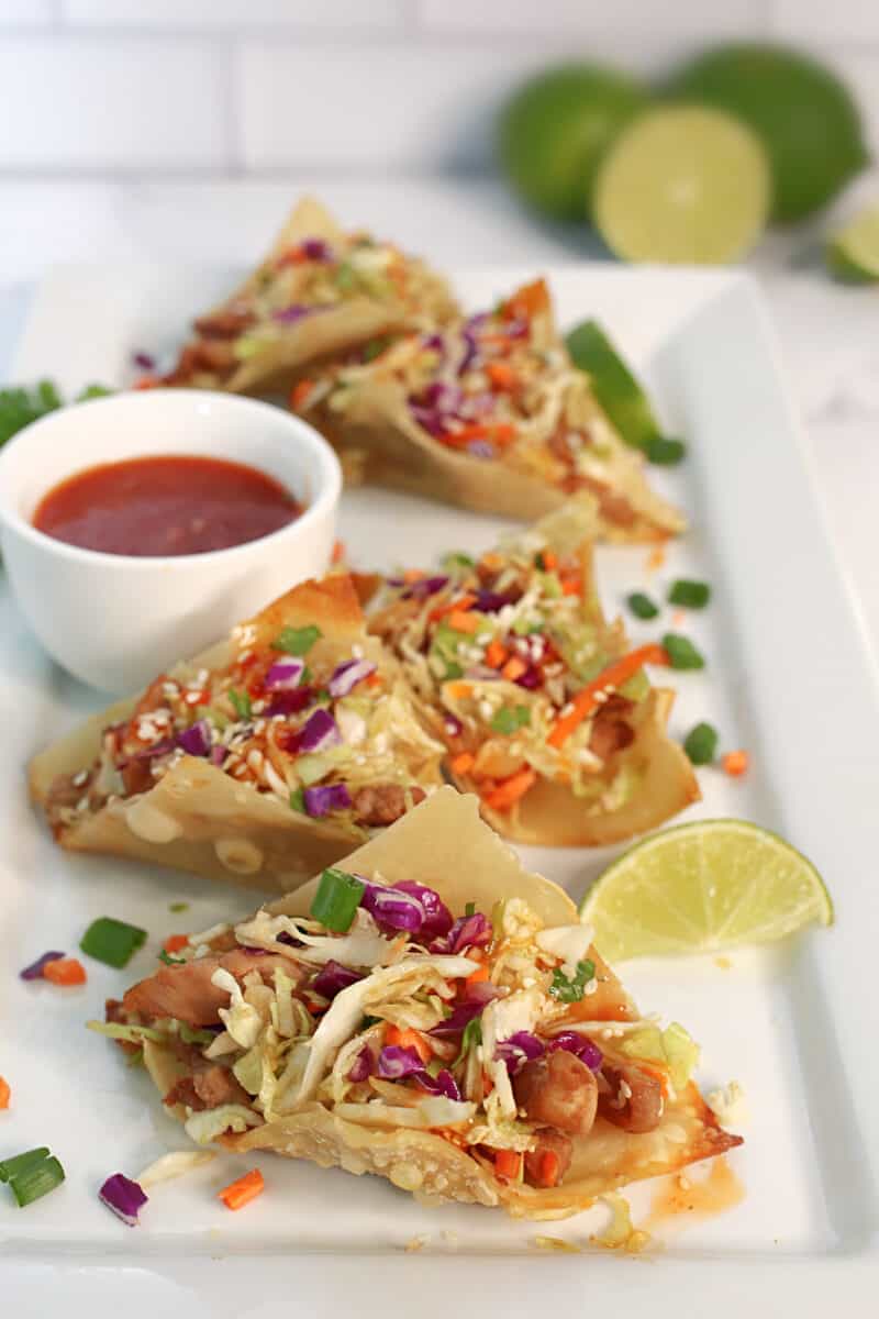 a white plate of chicken wonton tacos