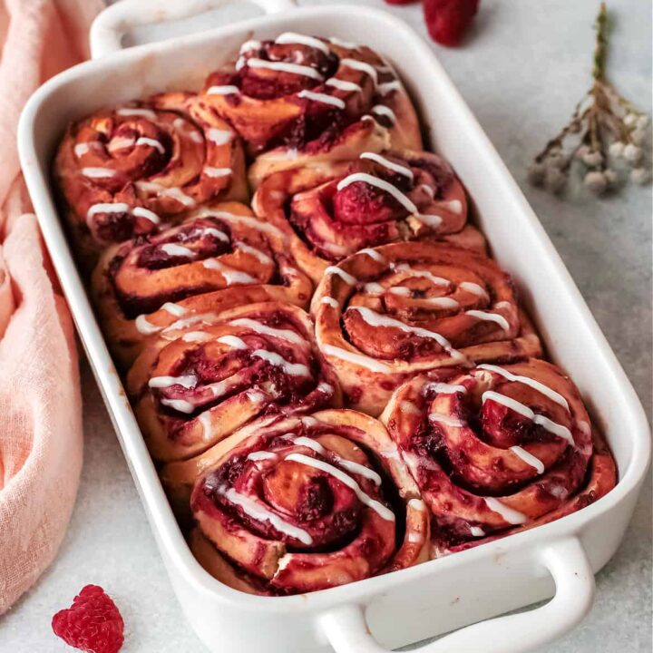 raspberry cinnamon rolls in a white baking dish on a table