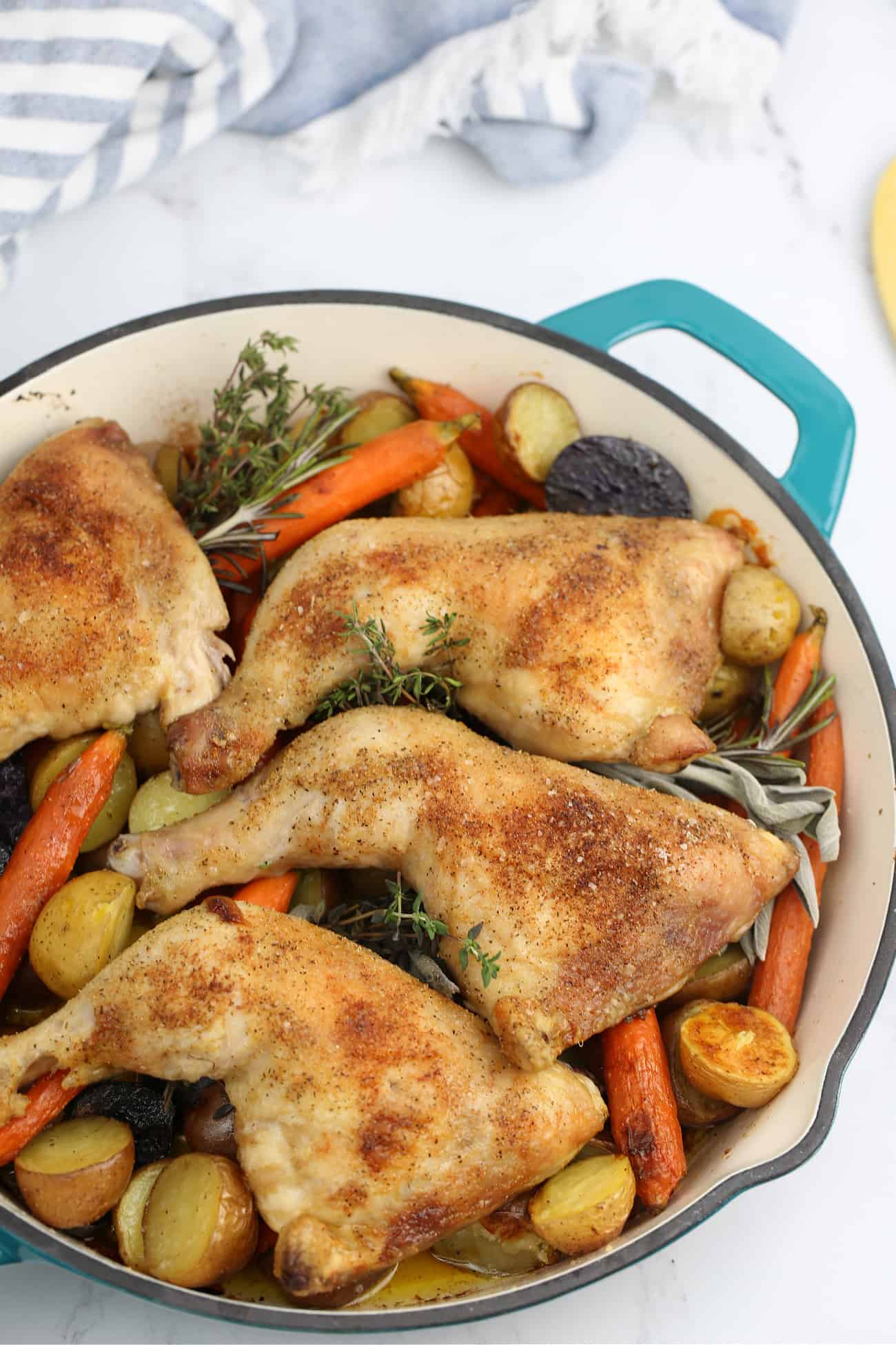 chicken quarters on cooked vegetables in a skillet