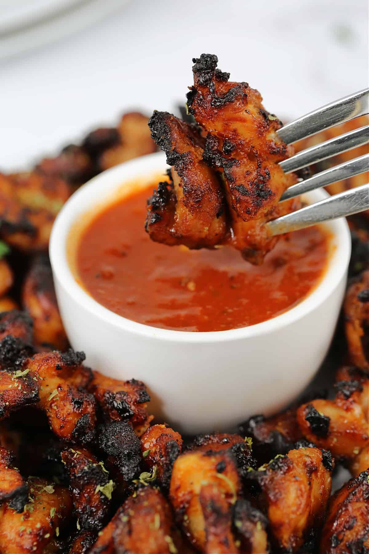 chicken on a form being dipped into marinara sauce