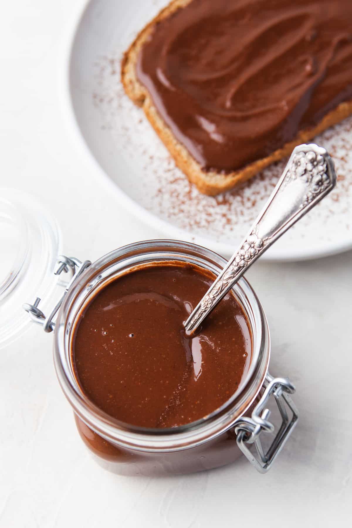 A jar of Nutella beside toast on a plate