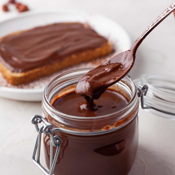 a spoon lifting up Nutella from a glass jar