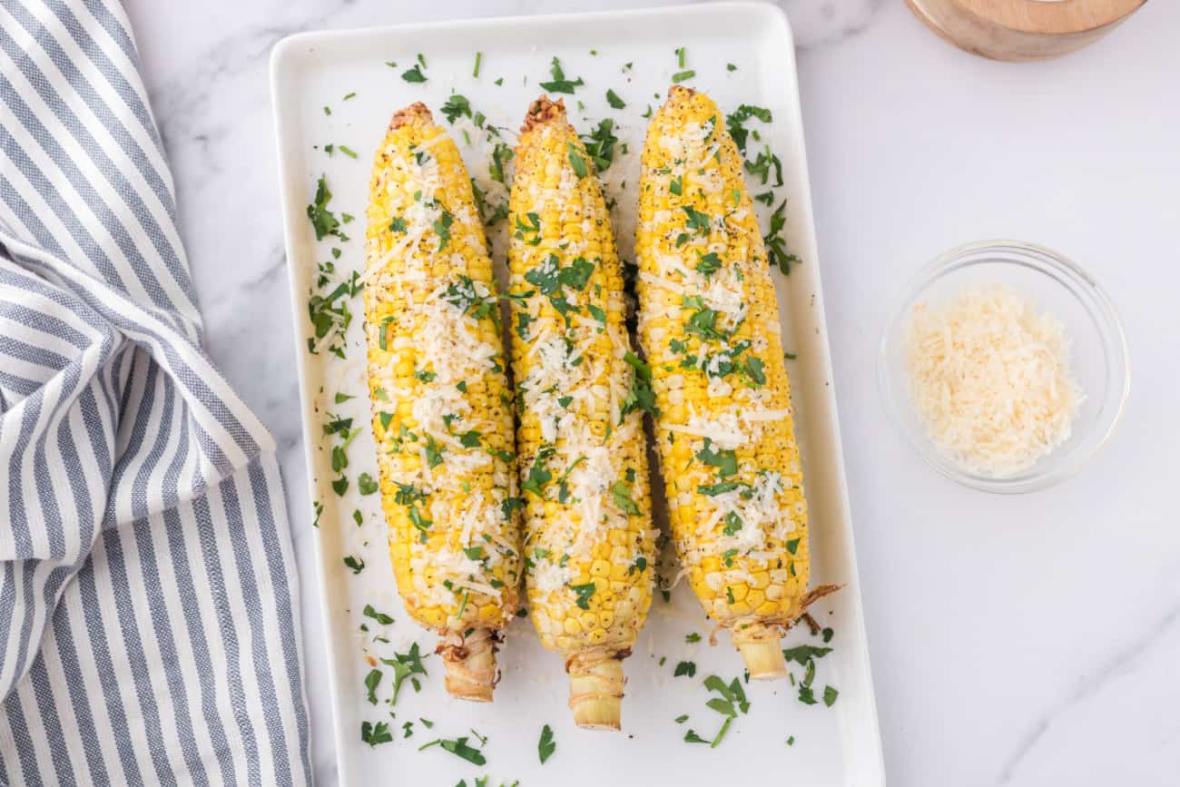 three cooked ears of corn on a white serving tray