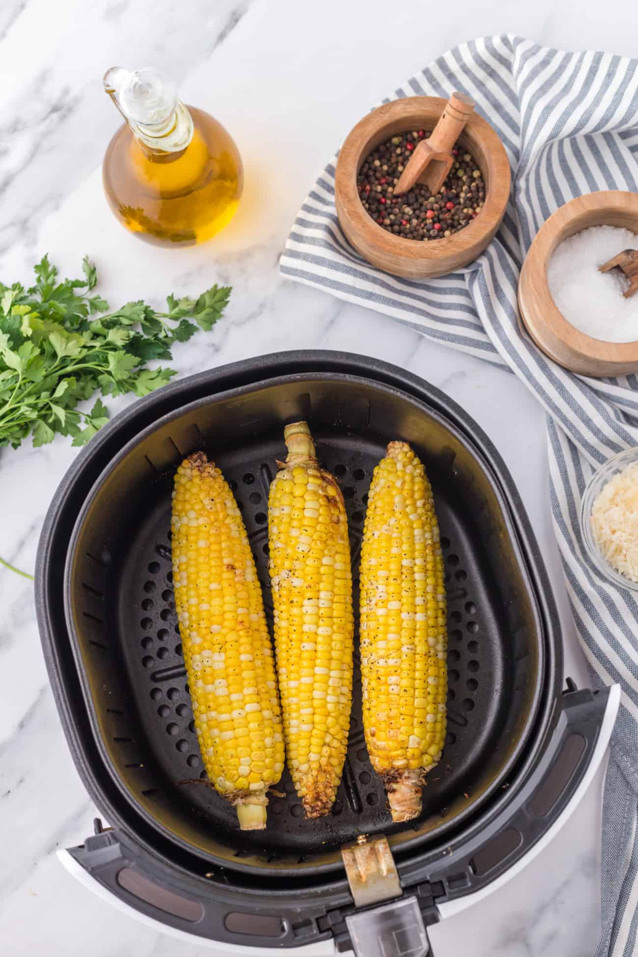 three ears of corn in an air fryer basket