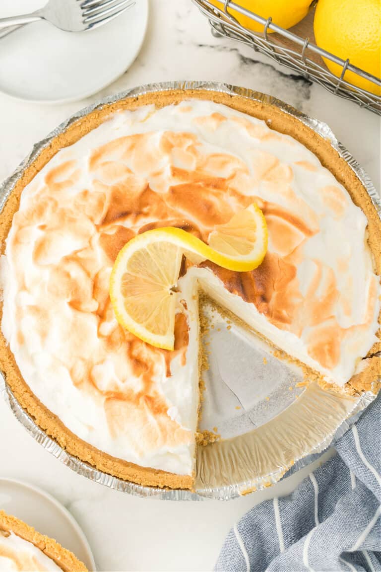 a lemon pie with a slice taken out with a slice of lemon on it