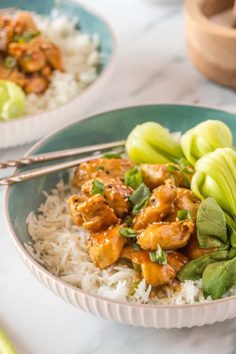 general tsos chicken in a blue bowl with rice and bok choy