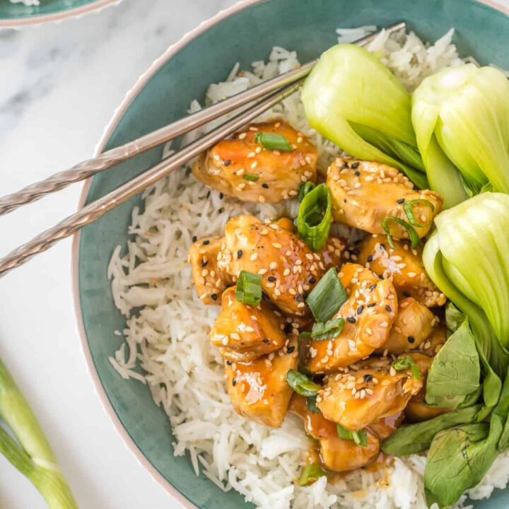 general tsos chicken in a blue bowl with rice and bok choy