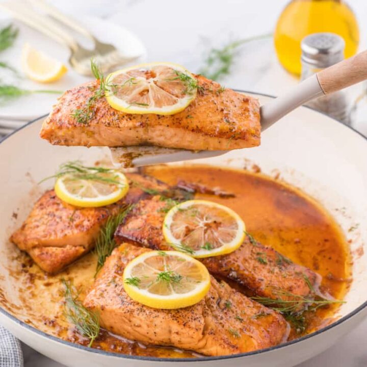 a pan of seared Lemon Salmon with a spatula lifting one piece up