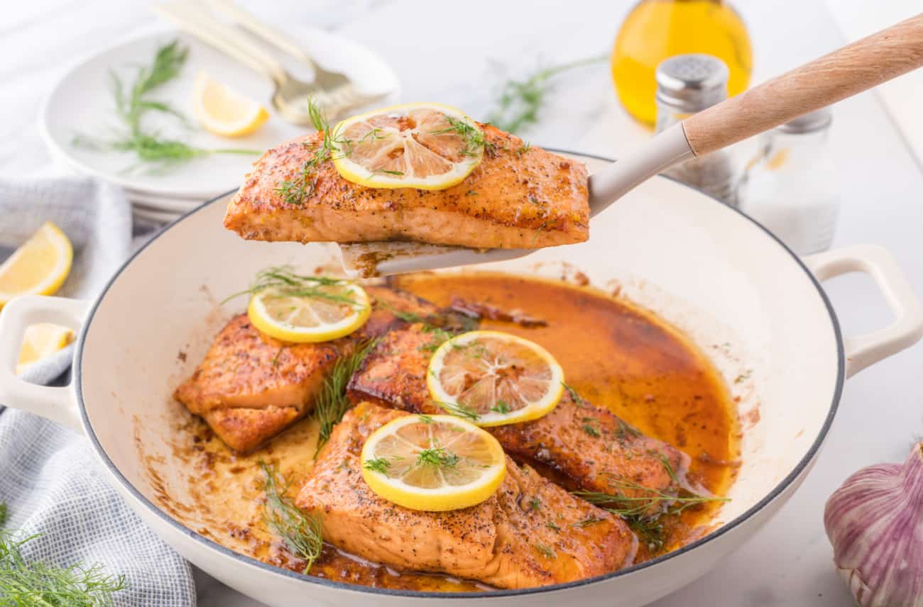 a pan of seared Lemon Salmon with a spatula lifting one piece up