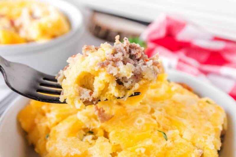 food on a fork with bowl, with sausage egg brunch casserole