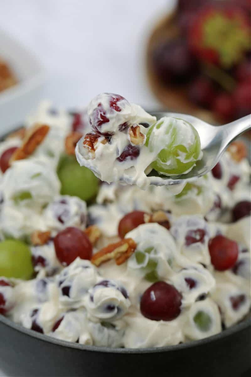 food on a spoon and in a bowl, with grape salad