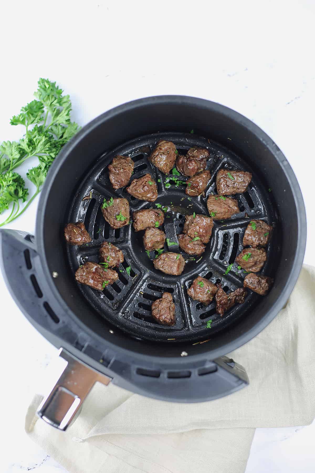 food in a an air fryer basket, with steak bites
